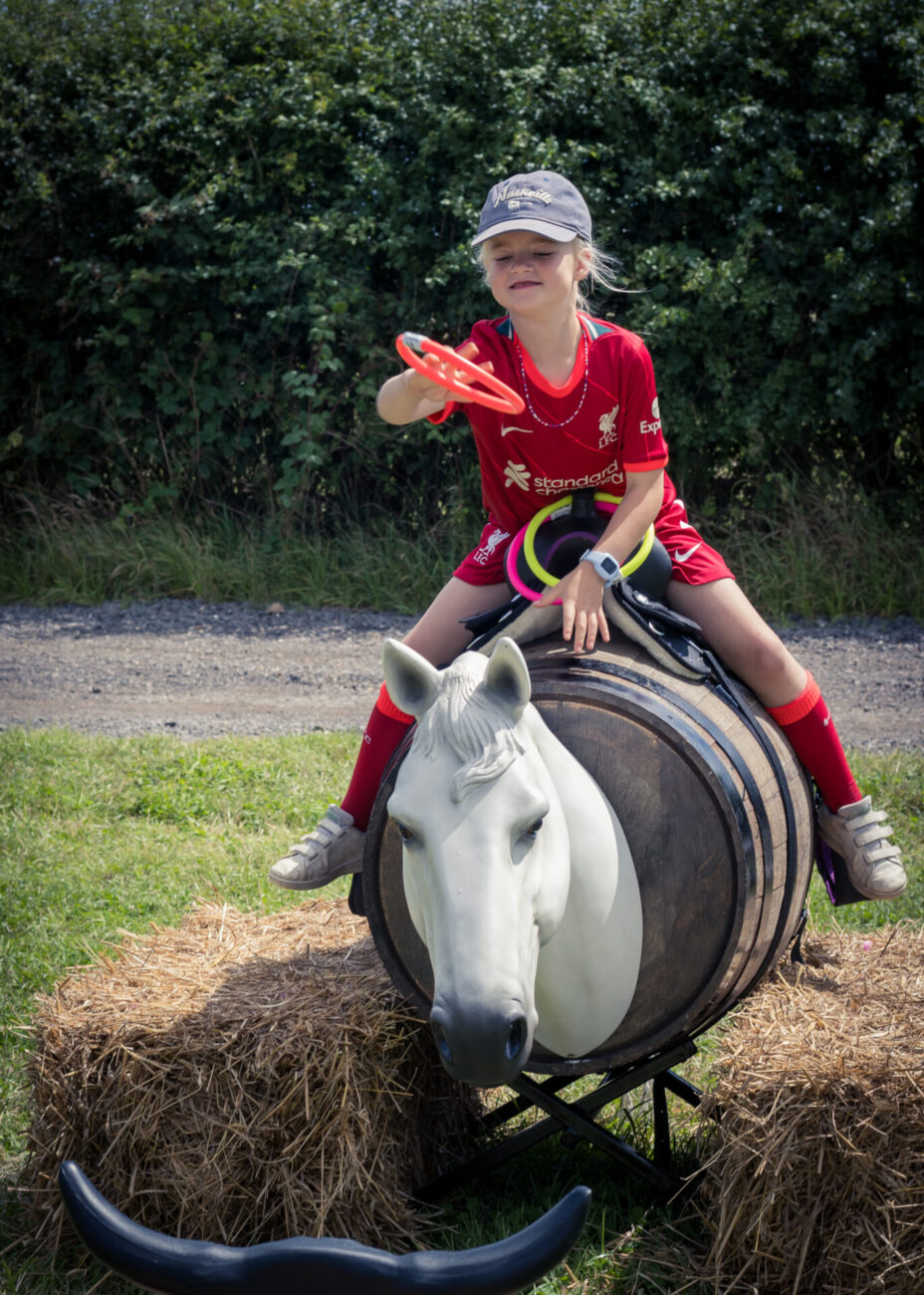 little girl on a horse barrel throwing hoops at a bulls horns at the patch mk