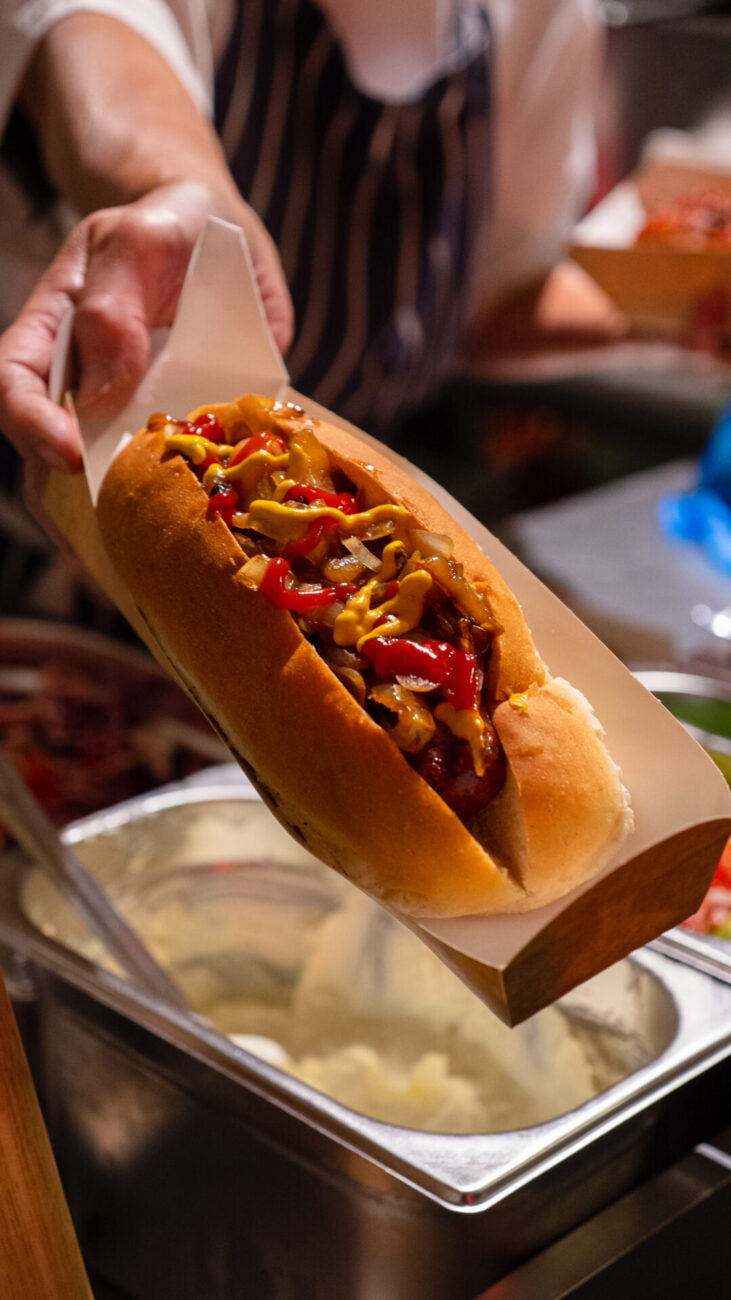 hot dog served in a white roll with ketchup, mustard and onion